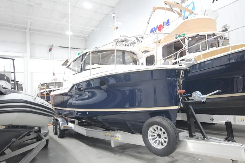 Slide: The Image of 2026 Ranger Tugs R-25 boat on trailer in showroom, side view. - 2