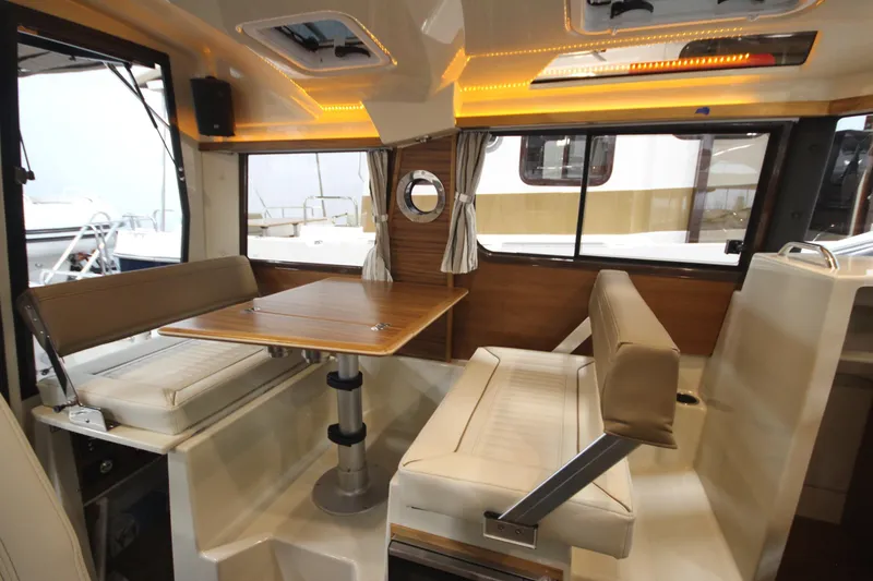 Slide: The Image of Interior of 2026 Ranger Tugs R-25, featuring a cozy dining area with wood accents. - 21