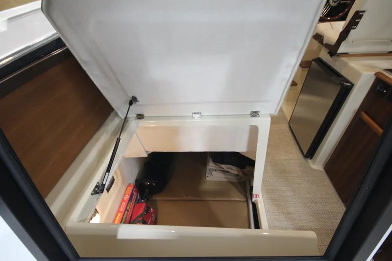 Slide: The Image of 2026 Ranger Tugs R-25 interior storage compartment with open hatch, revealing organized space. - 25