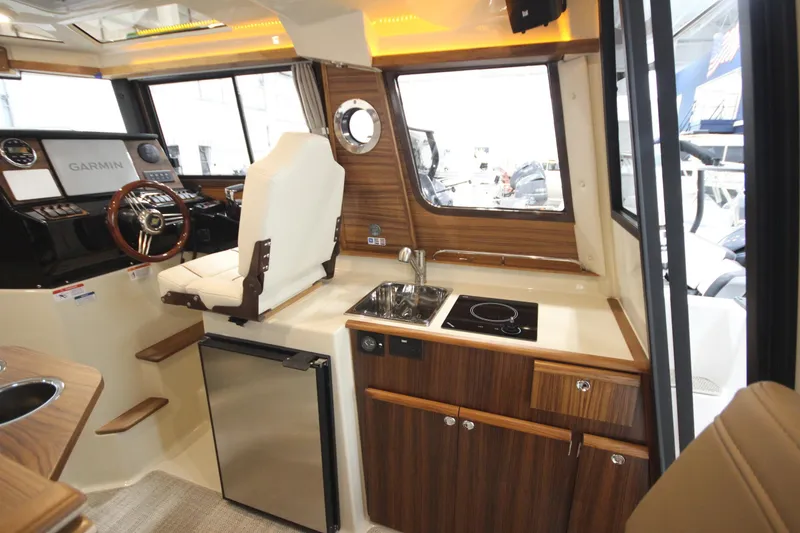 Slide: The Image of 2026 Ranger Tugs R-25 interior with helm, kitchenette, and modern wood finish. - 27