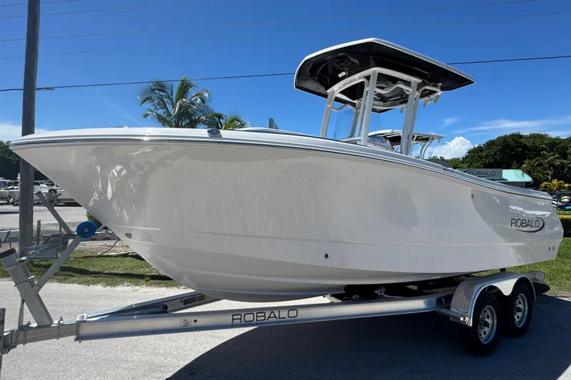 Slide: The Image of 2026 Robalo R232 Explorer boat on trailer, sunny day, palm trees in background. - 2
