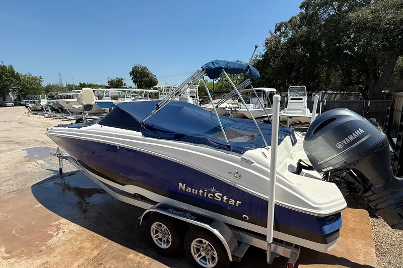 Slide: The Image of 2018 NauticStar 223 DC boat with Yamaha engine on trailer, parked outdoors. - 19