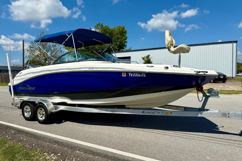 Slide: The Image of 2018 NauticStar 223 DC boat on trailer, blue and white, parked outdoors. - 5