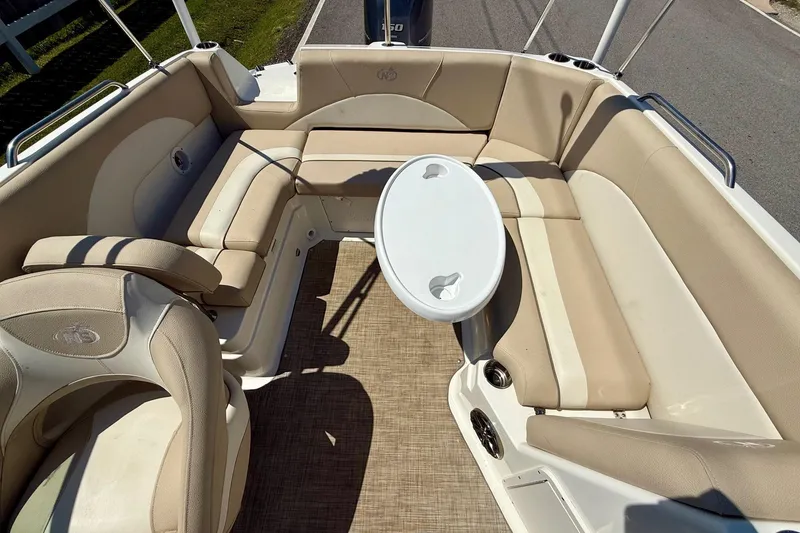 Slide: The Image of 2018 NauticStar 223 DC boat interior with beige seating and a small table. - 7
