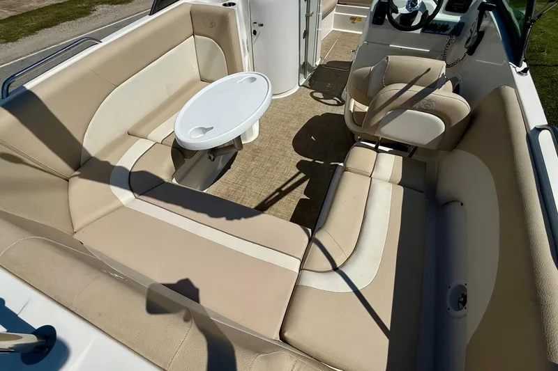 Slide: The Image of 2018 NauticStar 223 DC boat interior with beige seating and a small table. - 8
