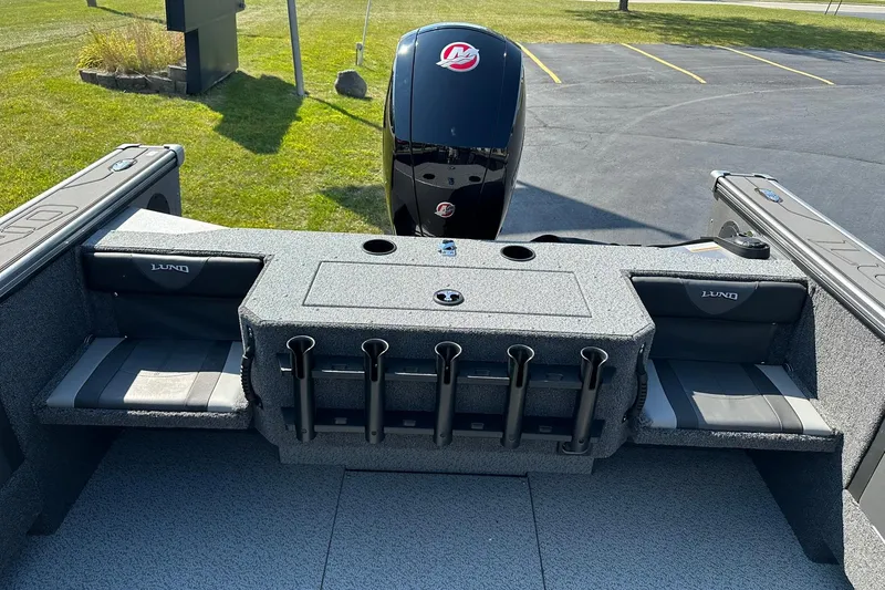Slide: The Image of 2026 Lund 1875 Fisherman boat interior with rod holders and seating, parked on grass. - 13