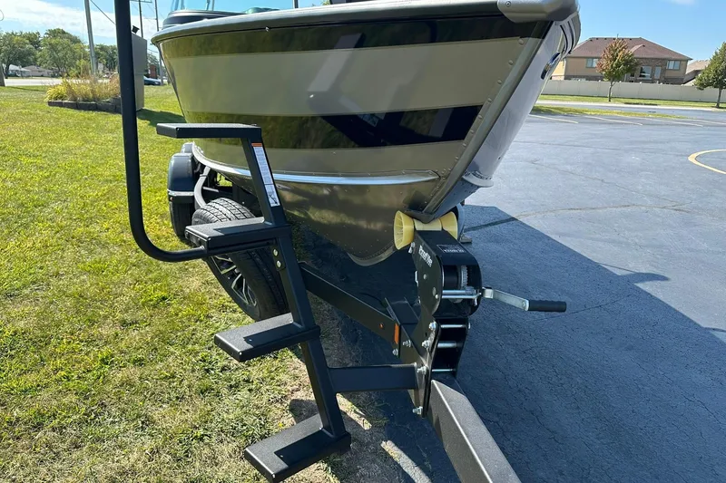 Slide: The Image of 2026 Lund 1875 Fisherman boat on trailer with ladder, parked on grass. - 6