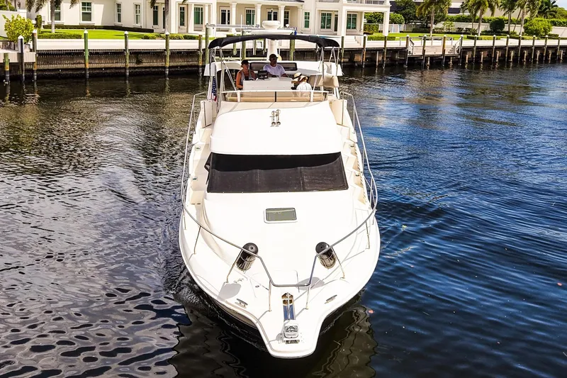 Slide: The Image of 2002 Silverton 352 Motor Yacht cruising on a calm waterway near a waterfront property. - 48