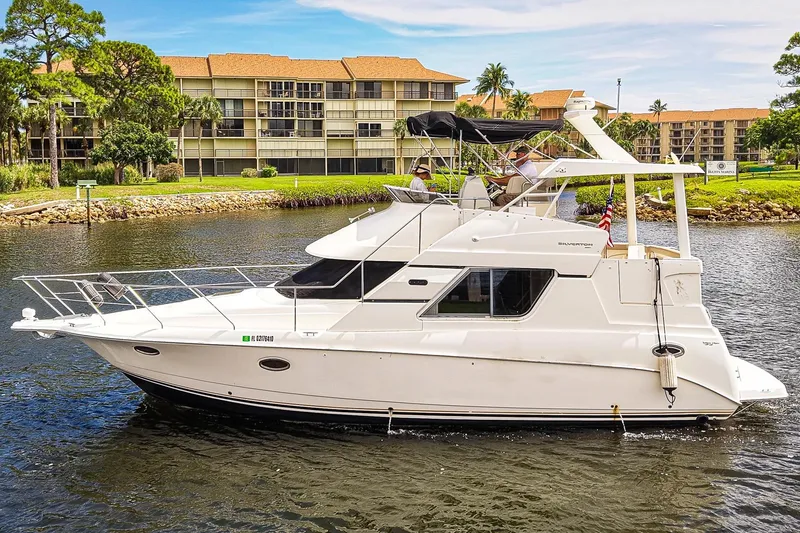 Slide: The Image of 2002 Silverton 352 Motor Yacht cruising on a scenic waterway near residential buildings. - 51