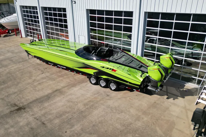 Slide: The Image of Bright green 2025 MTI 440X powerboat with dual engines on a trailer outside a garage. - 22