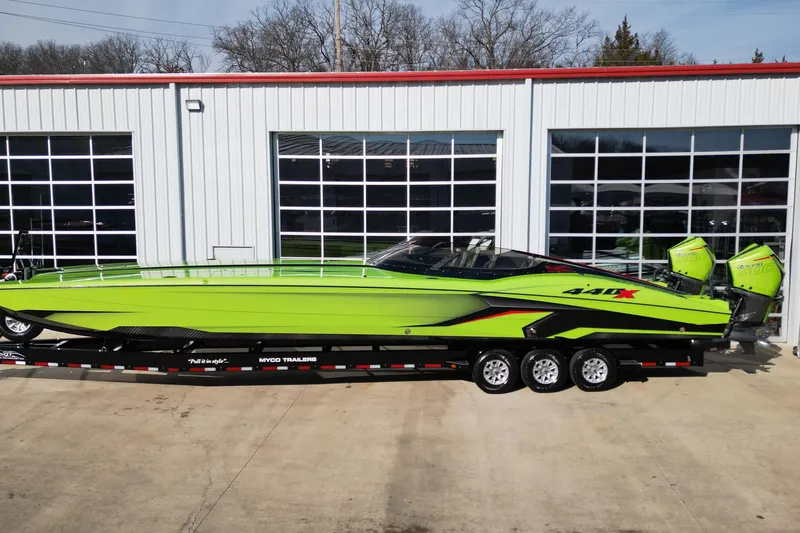 Slide: The Image of Bright green 2025 MTI 440X speedboat on trailer, parked outside a garage. - 23