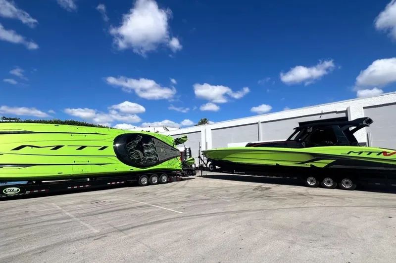 Slide: The Image of Bright green MTI 440X boats on trailers under a clear blue sky, 2025 model. - 39