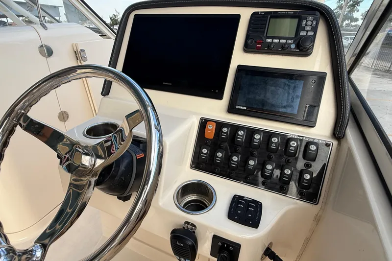 Slide: The Image of 2019 Grady-White Freedom 235 boat dashboard with steering wheel and control panel. - 16