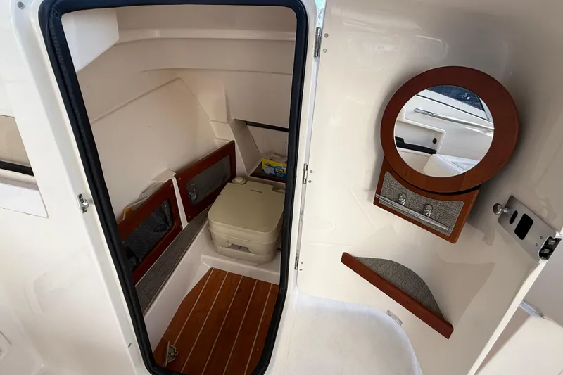 Slide: The Image of 2019 Grady-White Freedom 235 boat interior with compact toilet and wooden accents. - 17