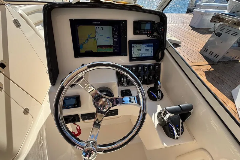 Slide: The Image of 2020 Grady-White Freedom 275 boat dashboard with steering wheel and navigation controls. - 15