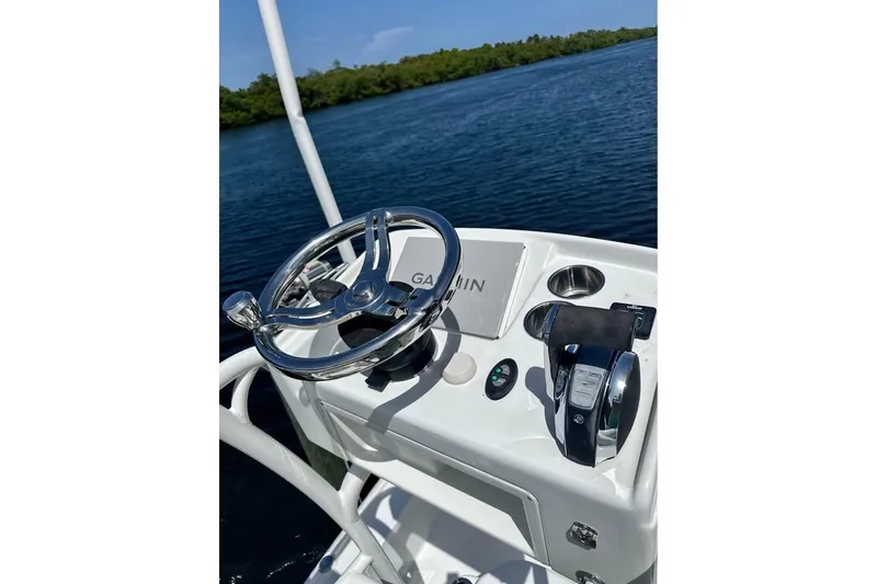 Slide: The Image of 2017 Yellowfin 24 Bay CE boat console with steering wheel and controls on water. - 11