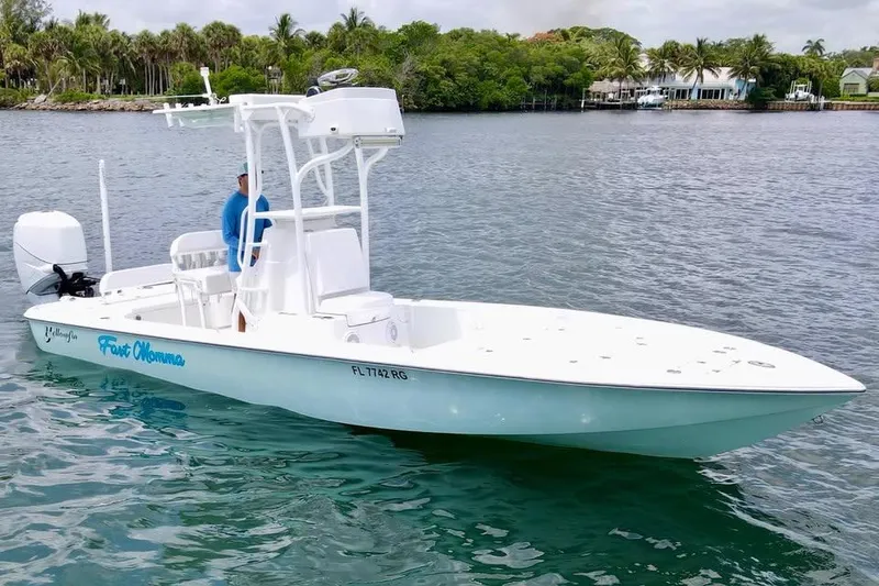 Slide: The Image of 2017 Yellowfin 24 Bay CE boat on calm water, surrounded by lush greenery. - 6