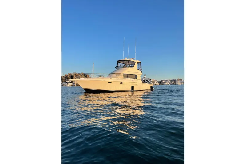 The Image of 2003 Silverton 42 Convertible yacht on calm water under clear blue sky. - 1