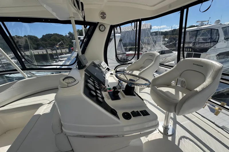 Slide: The Image of 2003 Silverton 42 Convertible yacht helm with dual captain chairs and panoramic windows. - 18
