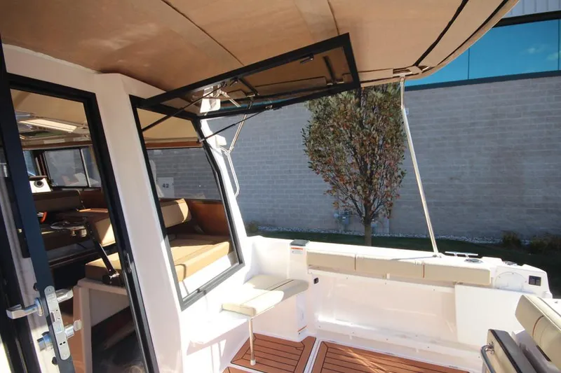 Slide: The Image of 2026 Ranger Tugs R-27 interior seating area with cushioned bench and window. - 18