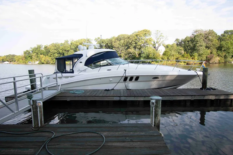 The Image of 2007 Sea Ray 40 Sundancer yacht docked by a serene lake with lush greenery. - 0