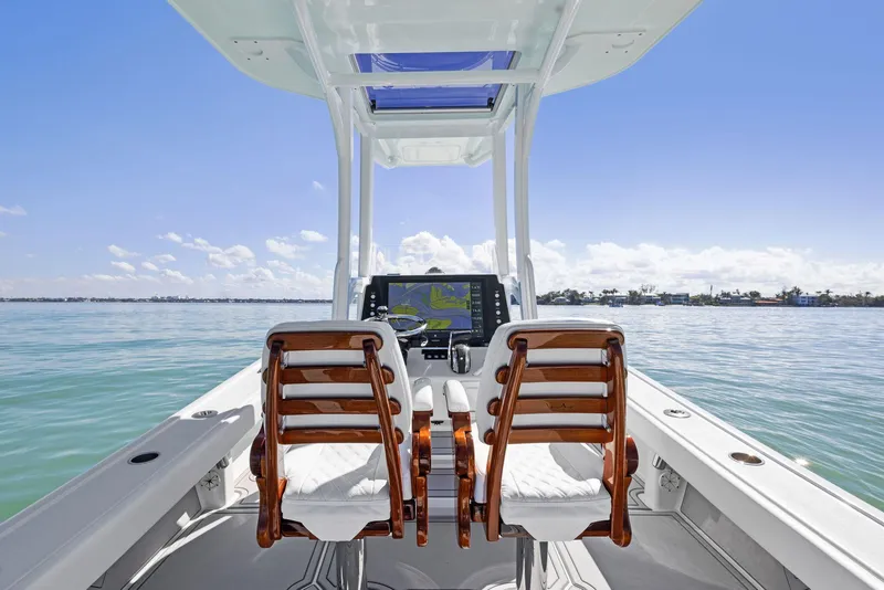 Slide: The Image of 2022 Barker Boatworks 26 Open, helm view, on calm water under clear blue sky. - 19