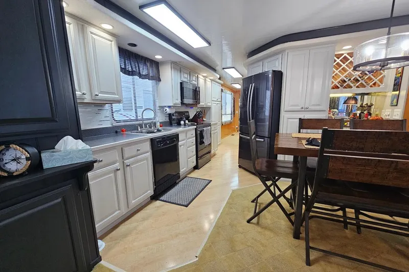 Slide: The Image of Modern kitchen interior in a 2000 Sumerset 16x75 houseboat, featuring sleek appliances and dining area. - 12