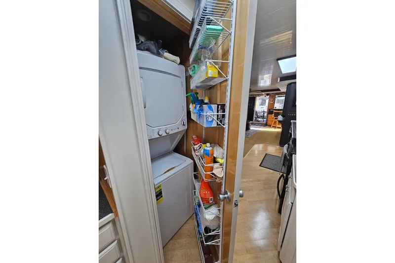 Slide: The Image of Laundry area with stacked washer-dryer and storage shelves in 2000 Sumerset 16x75 houseboat. - 14