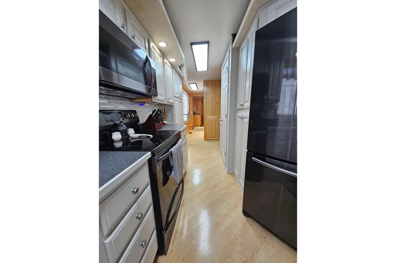 Slide: The Image of Modern kitchen interior in 2000 Sumerset 16x75 houseboat, featuring sleek appliances and wood flooring. - 23