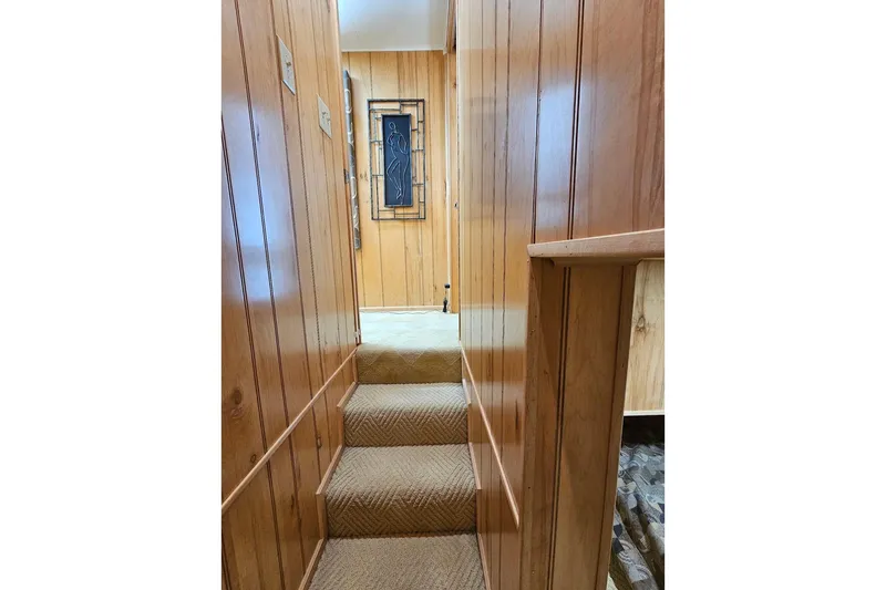 Slide: The Image of Wood-paneled staircase inside 2000 Sumerset 16x75 houseboat, featuring carpeted steps and wall art. - 39
