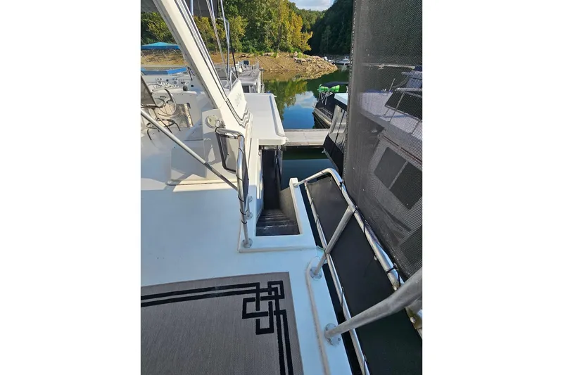 Slide: The Image of 2000 Sumerset 16x75 houseboat deck with railing, docked by a serene lake. - 65