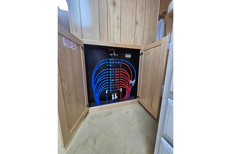 Slide: The Image of Plumbing system inside a 2000 Sumerset 16x75 houseboat, featuring organized blue and red pipes. - 67