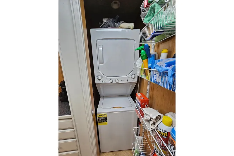 Slide: The Image of Stacked washer and dryer in a Sumerset 16x75 houseboat, surrounded by cleaning supplies. - 70