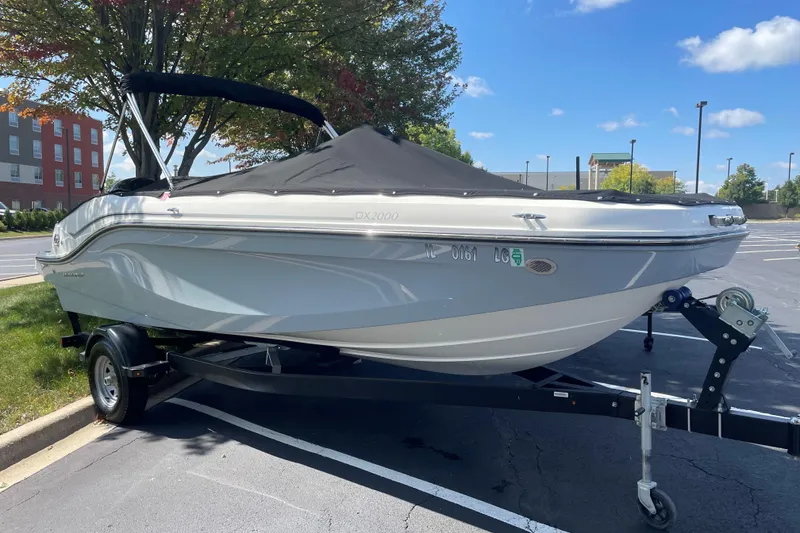 The Image of 2023 Bayliner DX 2000 boat on trailer, covered, parked outdoors. - 0