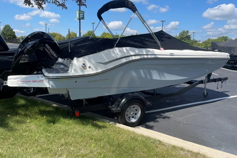 Slide: The Image of 2023 Bayliner DX 2000 boat on trailer, parked outdoors under a clear sky. - 3