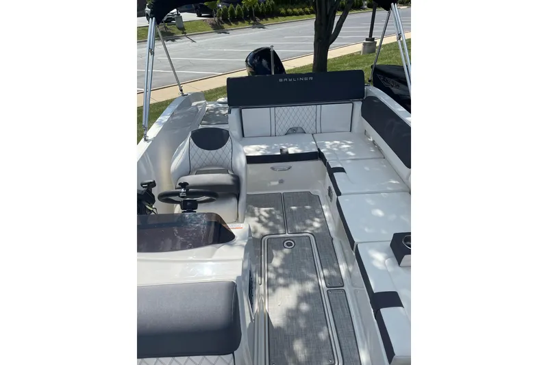 Slide: The Image of 2023 Bayliner DX 2000 boat interior with seating and helm, parked outdoors. - 6