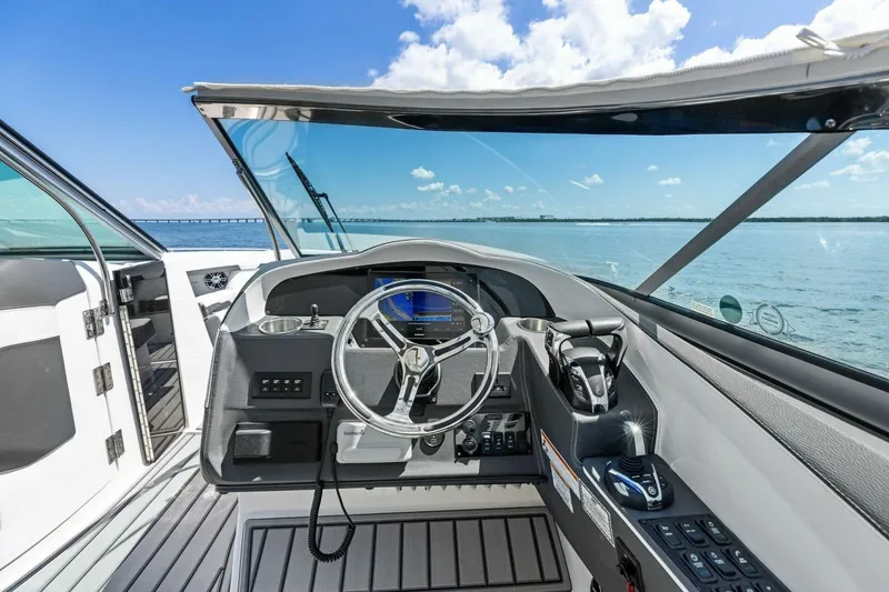 Slide: The Image of 2022 Regal 33 OBX boat cockpit with steering wheel, controls, and ocean view. - 16