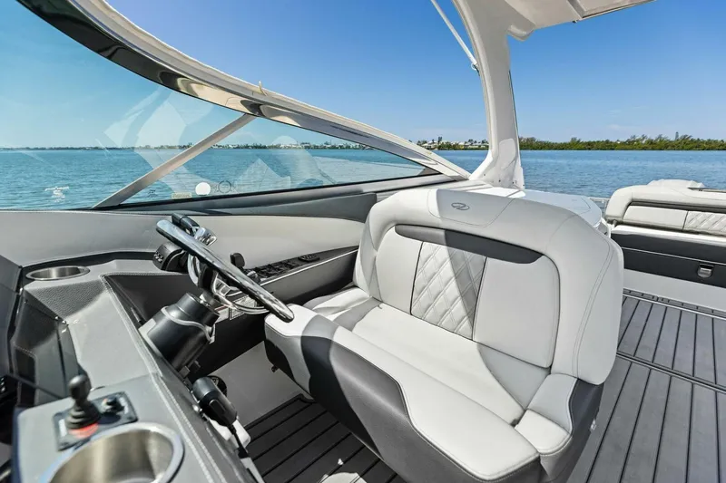 Slide: The Image of 2022 Regal 33 OBX boat interior with luxurious seating and steering, overlooking serene waters. - 23