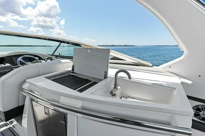 Slide: The Image of 2022 Regal 33 OBX yacht interior with sink and grill, overlooking serene ocean view. - 25