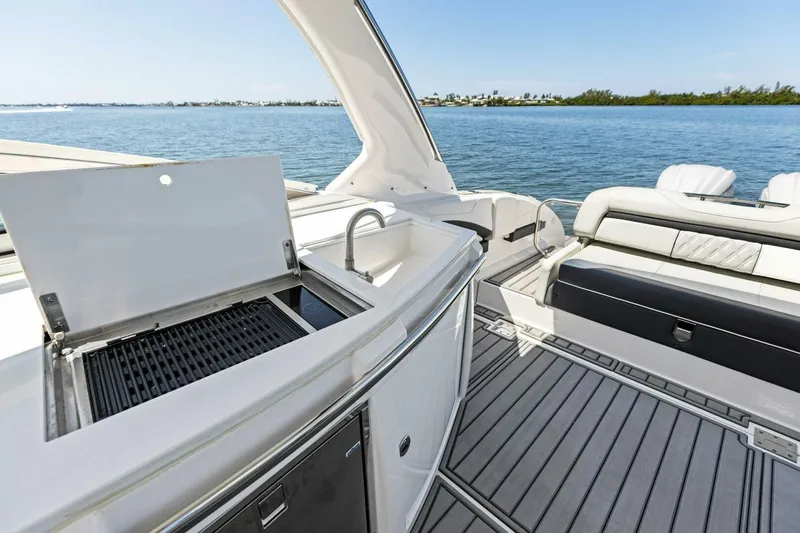 Slide: The Image of 2022 Regal 33 OBX boat interior with grill and seating, overlooking serene water. - 27