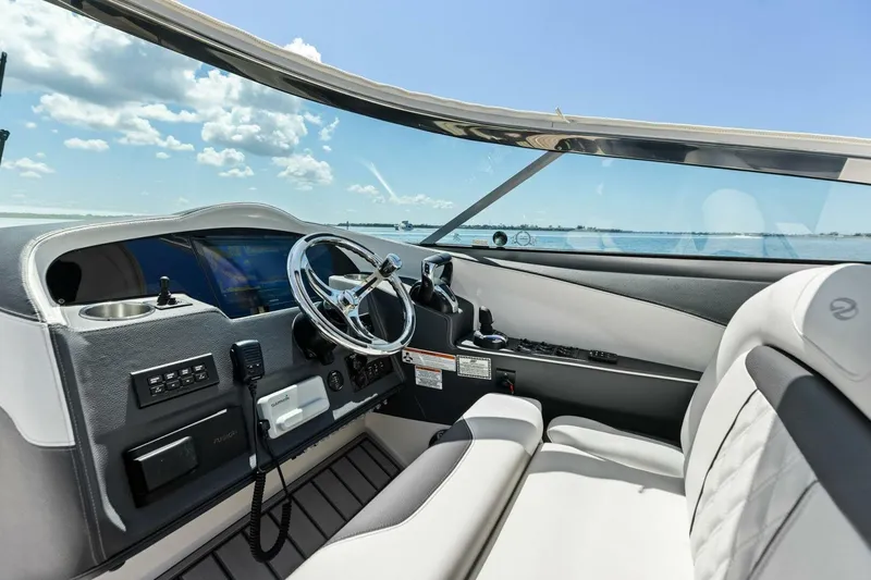 Slide: The Image of 2022 Regal 33 OBX boat interior with steering wheel and dashboard, overlooking the water. - 28