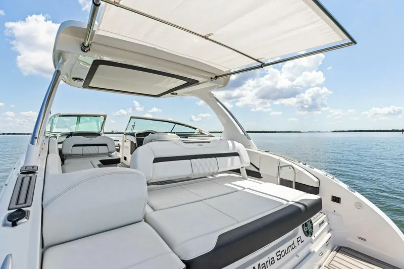 Slide: The Image of 2022 Regal 33 OBX luxury boat interior with spacious seating and canopy on calm water. - 40