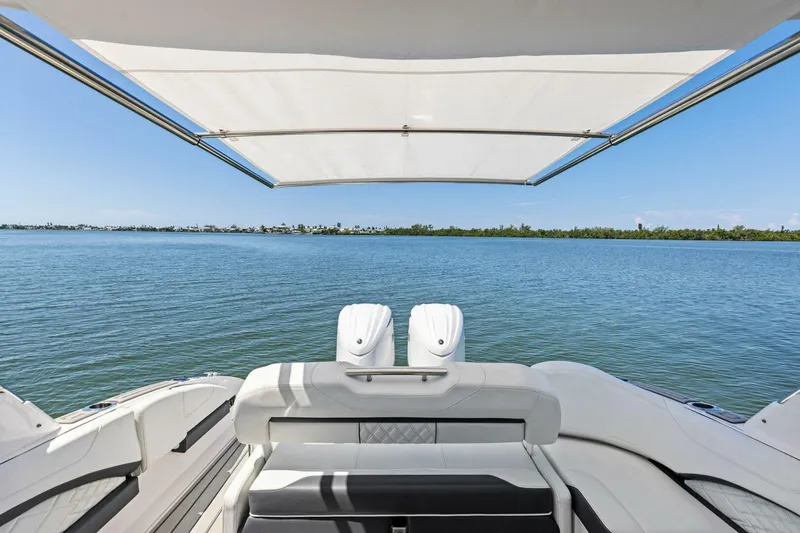 Slide: The Image of 2022 Regal 33 OBX boat with canopy, overlooking serene blue waters and distant shoreline. - 42
