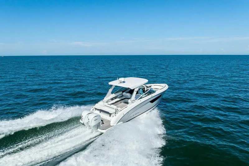 Slide: The Image of 2022 Regal 33 OBX boat cruising on open ocean under clear blue sky. - 49