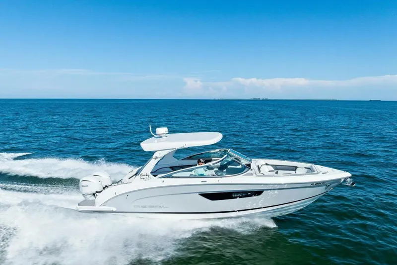 Slide: The Image of 2022 Regal 33 OBX boat cruising on open blue water under clear sky. - 54