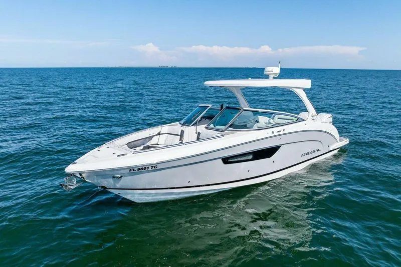 Slide: The Image of 2022 Regal 33 OBX boat cruising on open water under clear blue skies. - 59