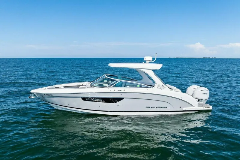 Slide: The Image of 2022 Regal 33 OBX boat cruising on open water under clear blue skies. - 60