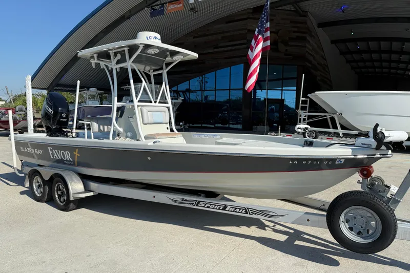 Slide: The Image of 2016 Blazer Bay 2420 Professional boat on trailer, parked outside a showroom. - 2
