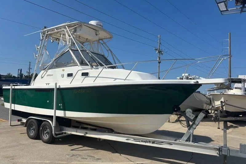 The Image of 2000 Shamrock 260 Express boat on trailer, green and white hull, parked outdoors. - 0