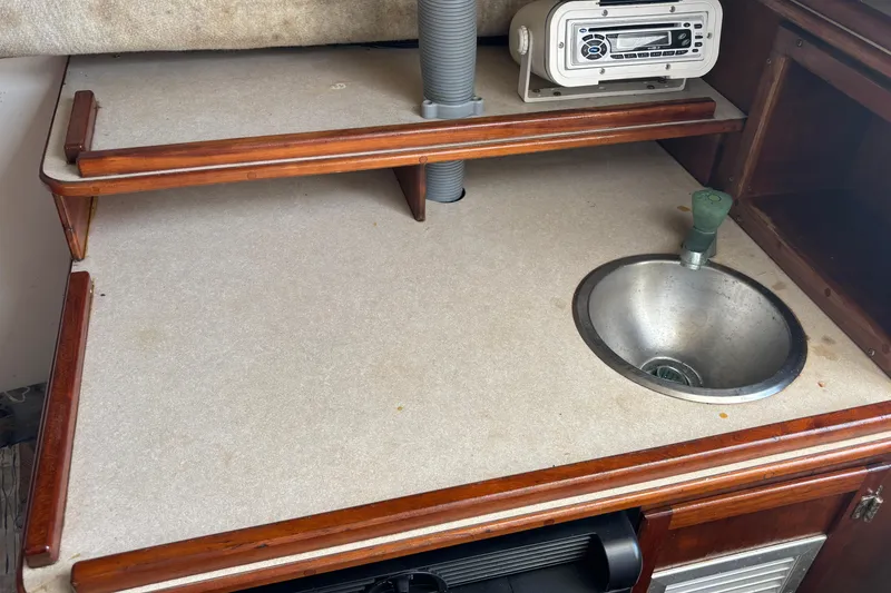 Slide: The Image of 2000 Shamrock 260 Express boat interior with sink and radio on wooden counter. - 12